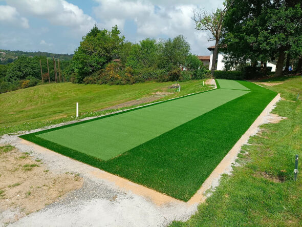 Metro New York Outdoor tee line consisting of one continuous green synthetic grass strip surrounded by trees